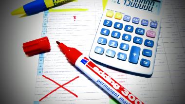 Projektliste mit Rotstift und Taschenrechner